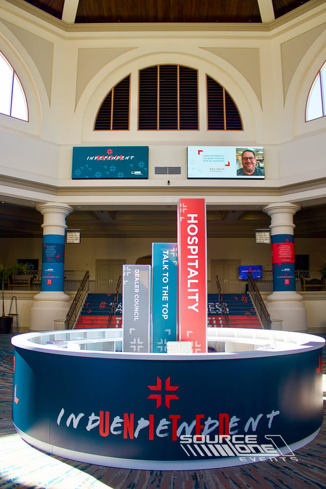 Central registration and information desk welcoming attendees inside a convention center rotunda.