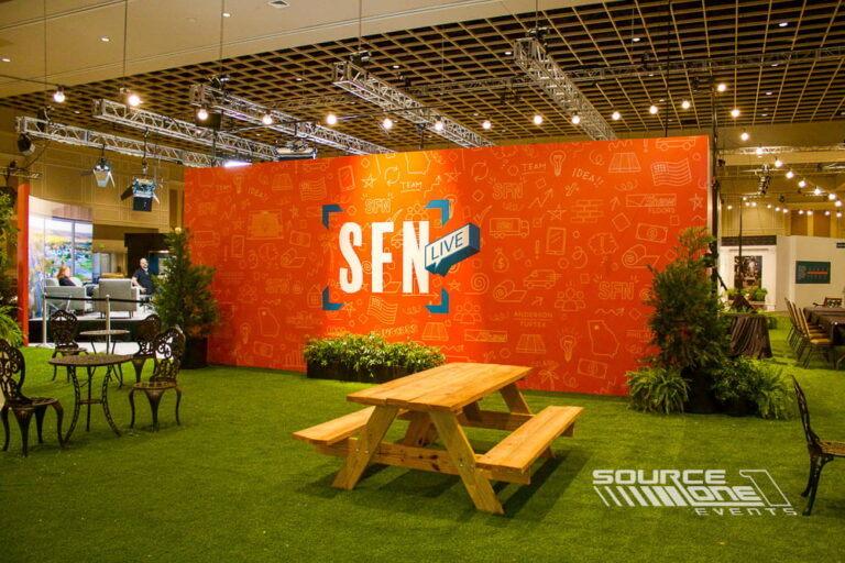 Stylish networking lounge featuring bright orange branded graphics, soft seating, and collaborative meeting areas.