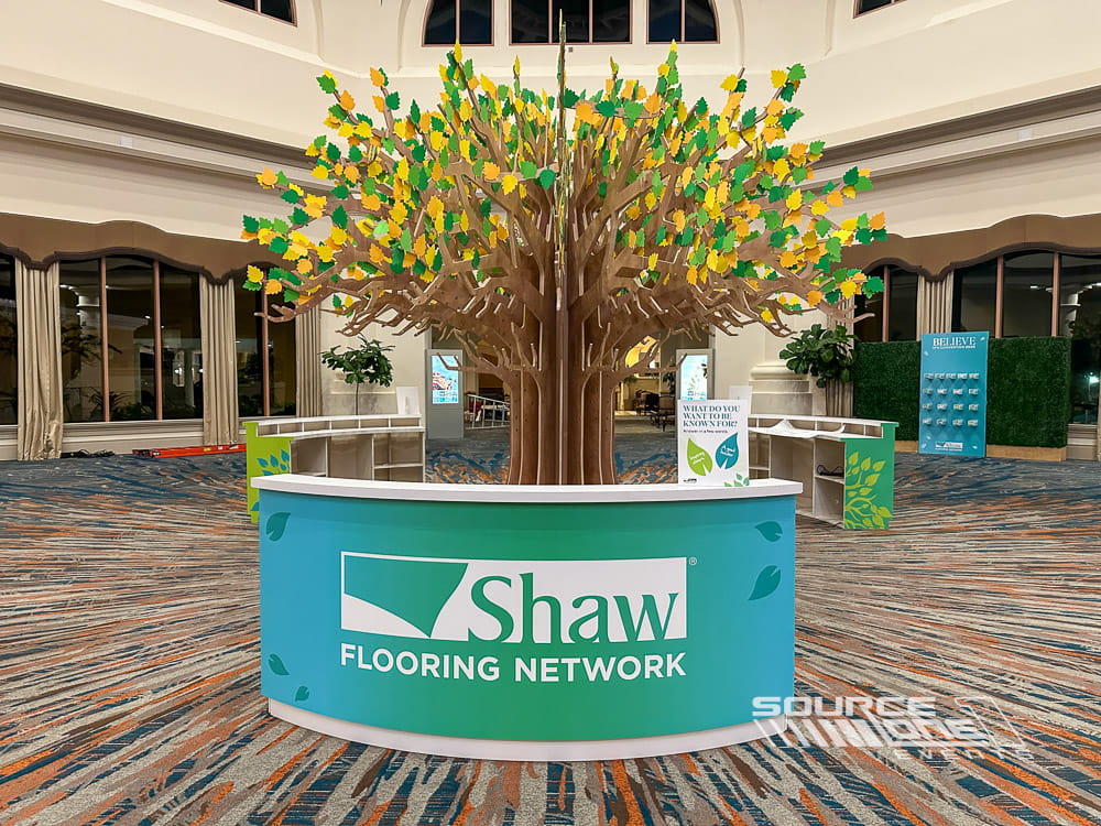 Custom branded counters and decorative tree display creating an engaging conference registration experience.