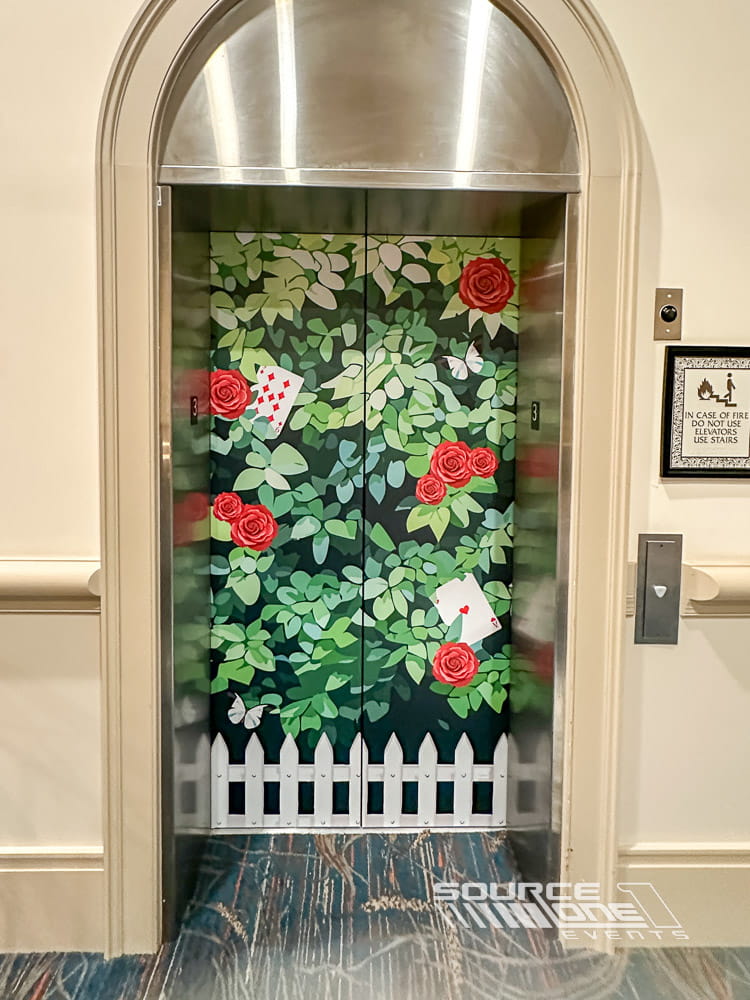 Exterior elevator entrance enhanced with colorful floral-themed environmental graphics creating an engaging attendee experience.