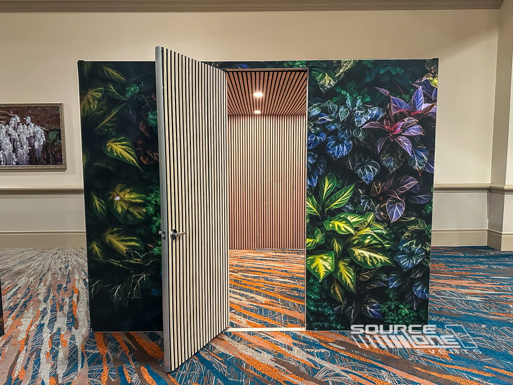 Custom-built soundproof meeting room featuring natural wood finishes, green botanical graphics, and acoustic wall construction for private conversations.