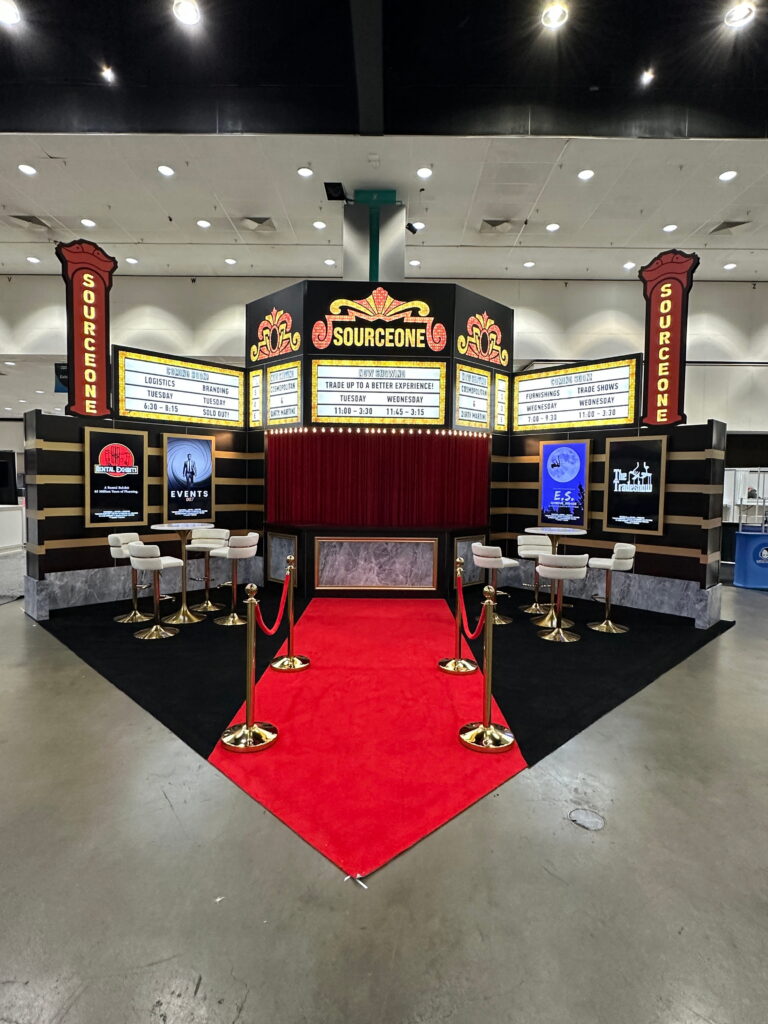 Large experiential trade show booth with theatrical entrance, illuminated signage, themed graphics, and immersive exhibit design.
