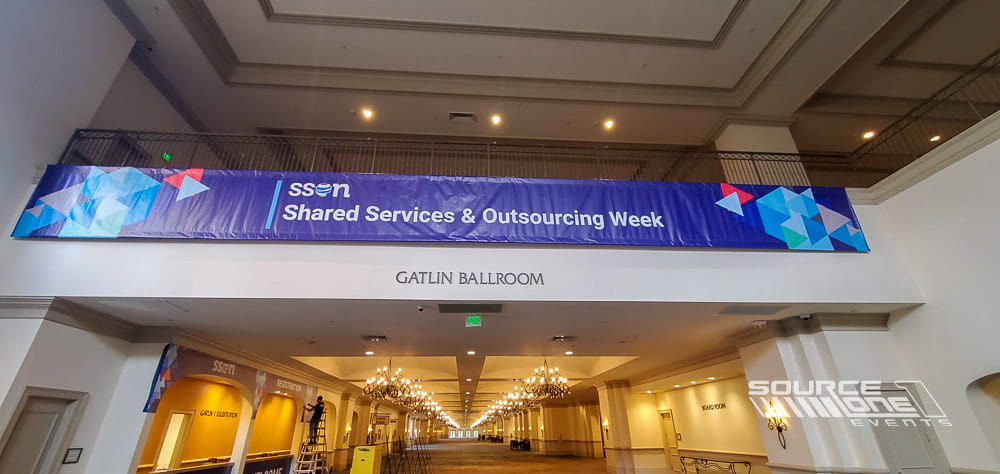Large suspended cube signs with illuminated United Airlines branding hanging above the trade show floor for wayfinding and brand visibility.
