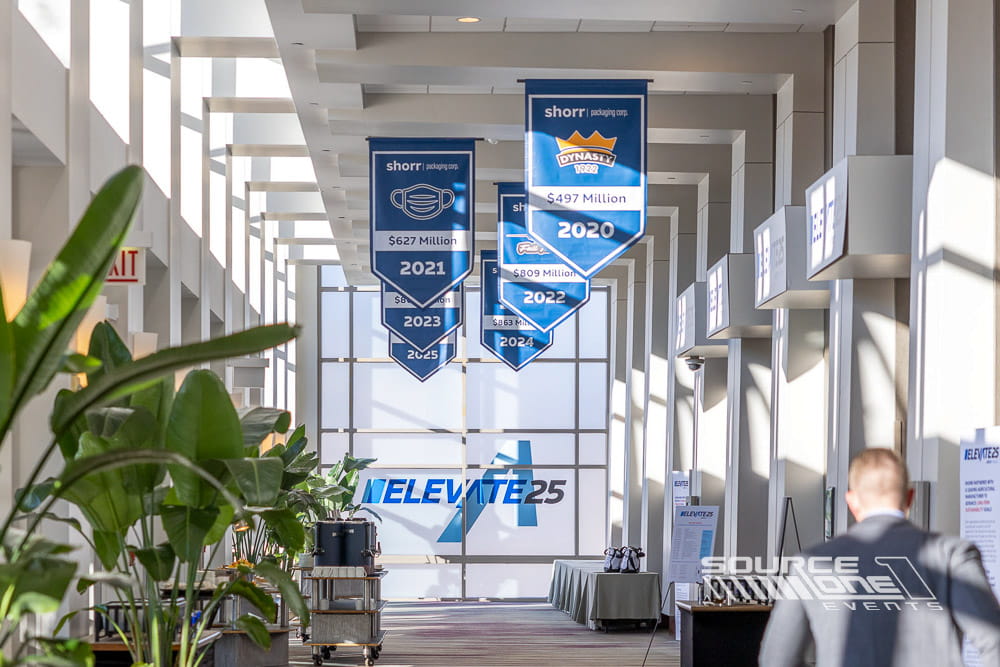 Long suspended banner spanning the convention center hallway with colorful SneakerCon event branding and sponsor graphics.