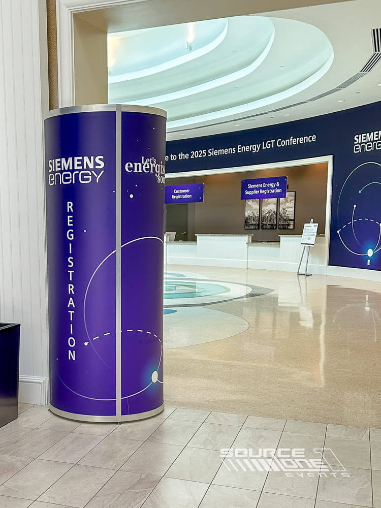 Curved blue illuminated tower display showcasing Siemens Energy branding at a corporate conference registration area designed by Source One Events.