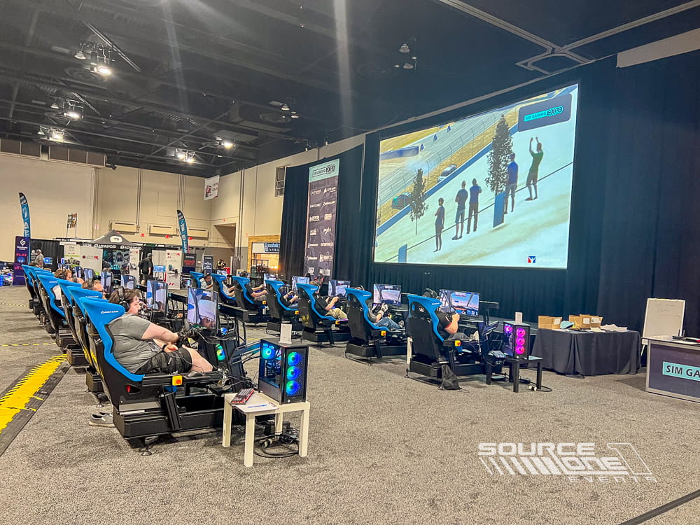 Wide-angle view of an esports competition arena with stage lighting, audience seating, and digital presentation screens.
