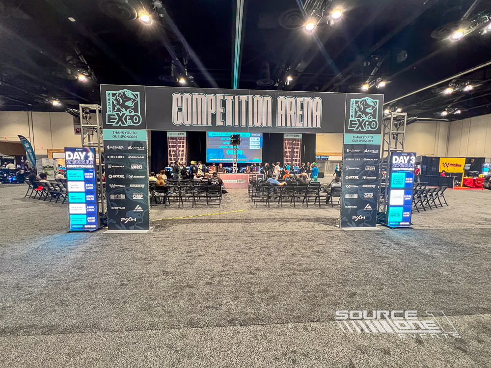 Large esports competition arena featuring illuminated gaming stage, branded LED graphics, spectator seating, and tournament play.