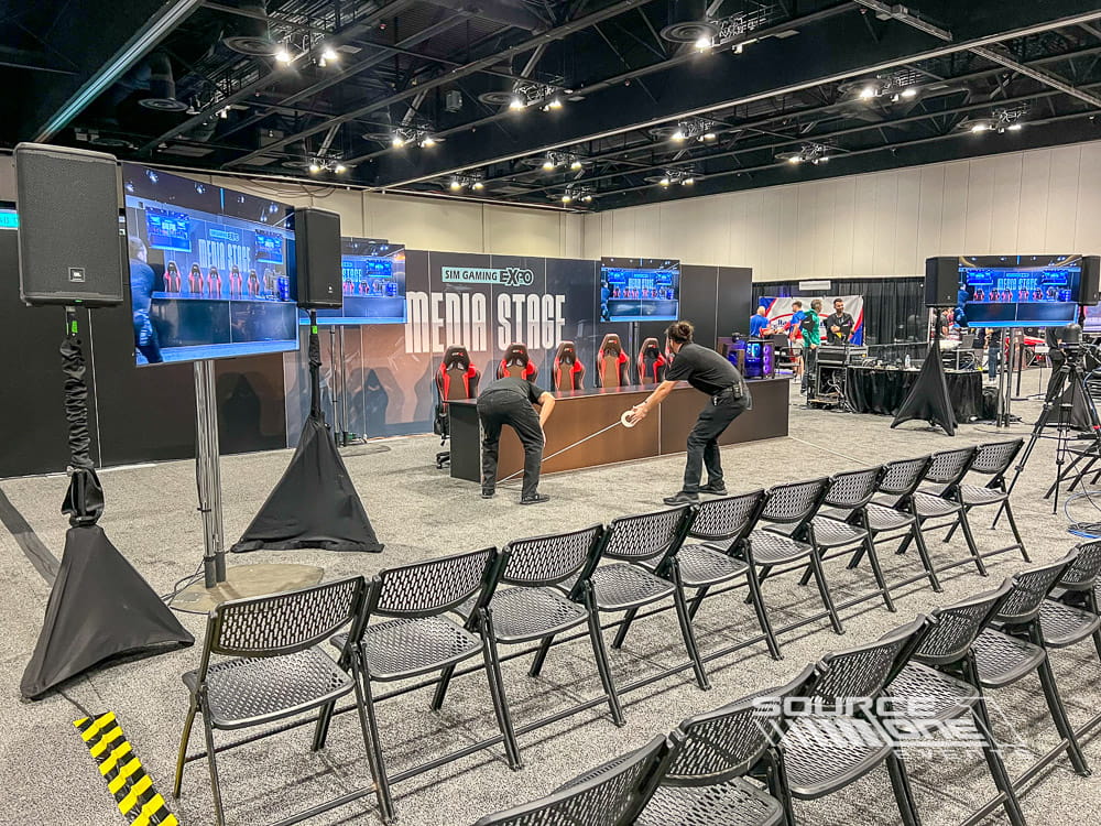Professional media stage with large LED screens, lighting, and audience seating for live presentations and esports programming.