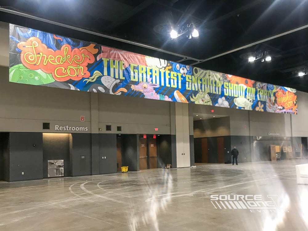 Large hanging entrance banner welcoming attendees into the conference ballroom with custom branded graphics.