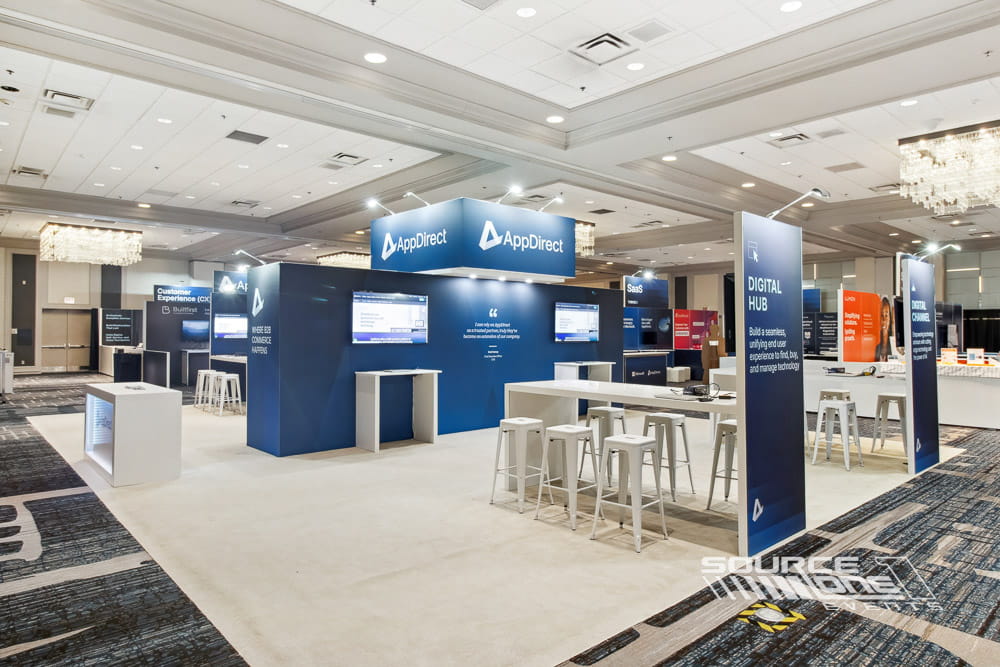 Premium custom booth with illuminated logo, branded graphics, and open visitor engagement space.