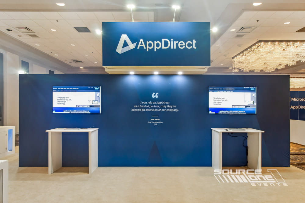 Large custom trade show exhibit featuring overhead branding, product demonstration stations, and interactive technology displays.