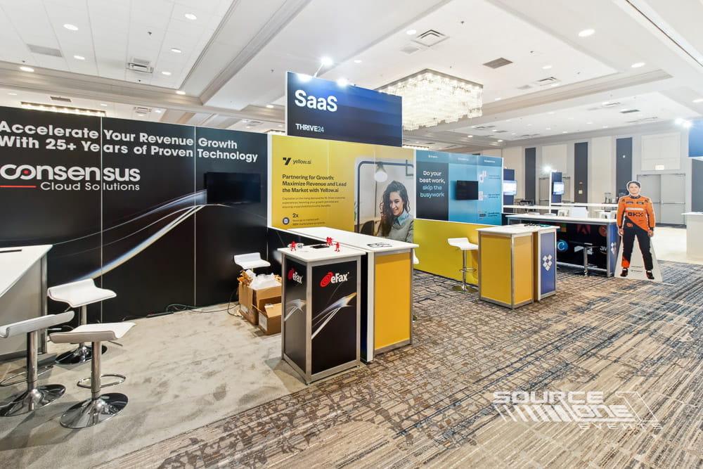 Corporate exhibit featuring blue architectural branding, digital displays, and collaborative meeting counters.