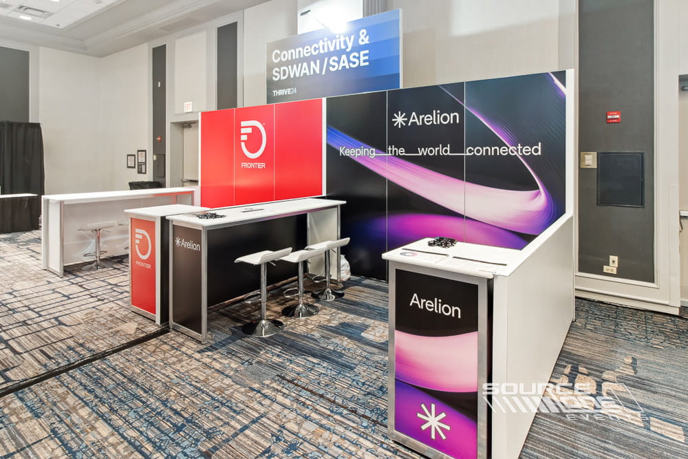 Contemporary hardwall booth showcasing curved architectural graphics, digital monitor, and attendee consultation area.