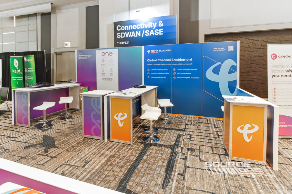 Custom exhibit featuring blue branding, white counters, product displays, and professional trade show environment.