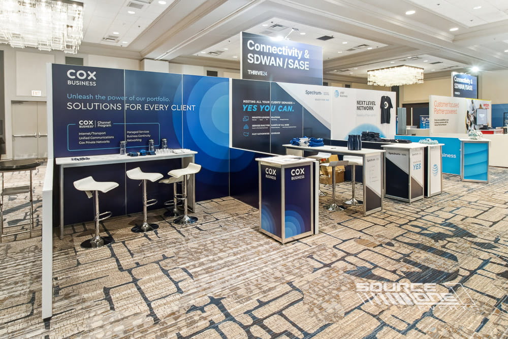 Premium hardwall exhibit booth with integrated shelving, branded graphics, meeting space, and digital presentation screen.