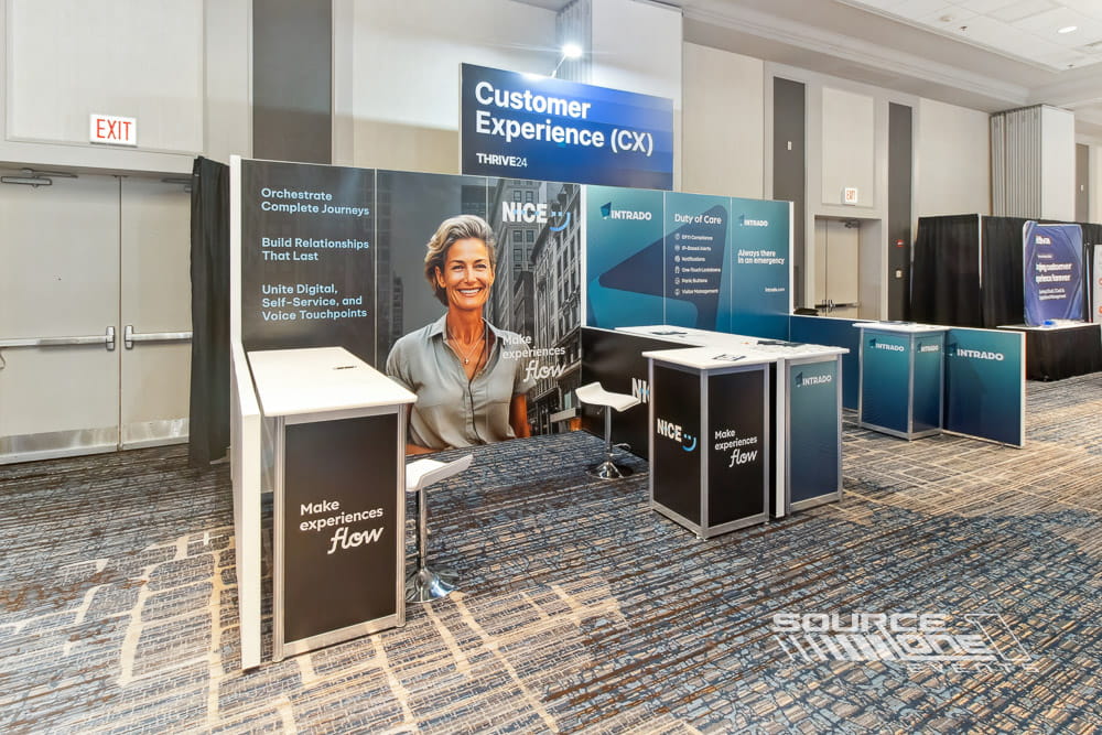 Corporate trade show booth featuring reception desk, branded graphics, and comfortable attendee consultation area.