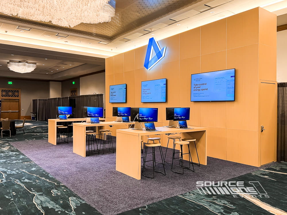 Contemporary custom exhibit with illuminated branding, digital screens, reception counter, and private meeting areas.