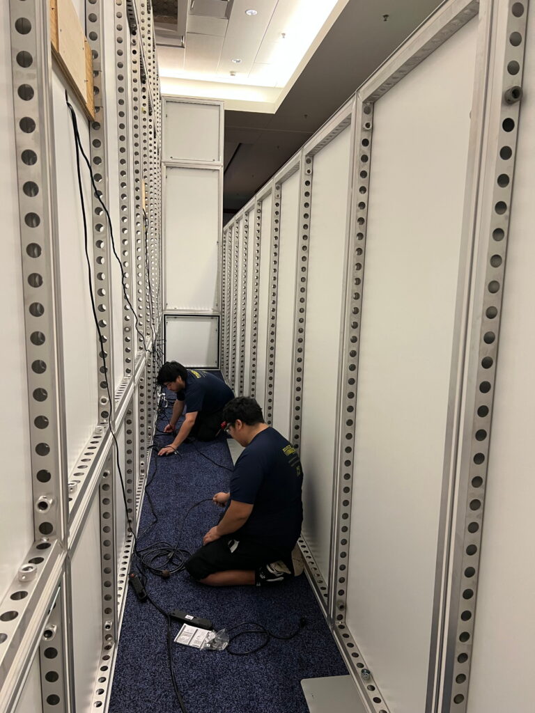 Event crew assembling modular exhibit structures during trade show installation.