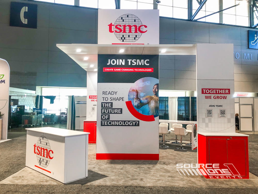 Large custom trade show exhibit featuring suspended signage, digital displays, and branded meeting spaces for exhibitors.