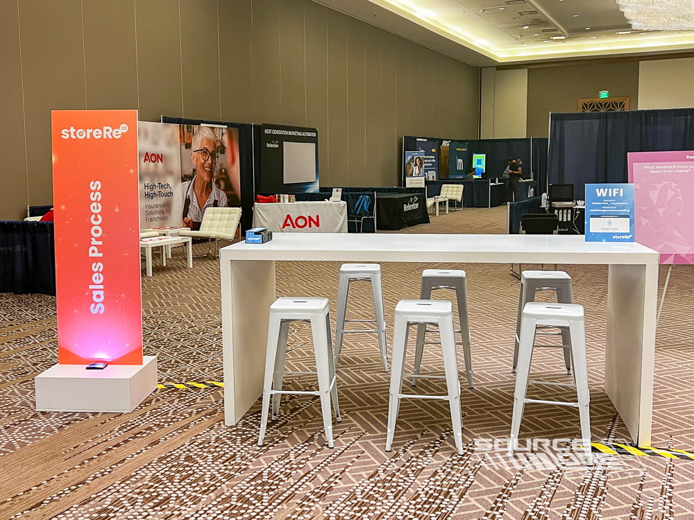 Branded hospitality counter with stools creating a casual meeting space on a trade show floor.