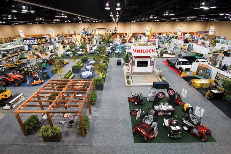 Wide view of a busy trade show floor featuring exhibitor booths, attendees, and event displays inside a convention center.