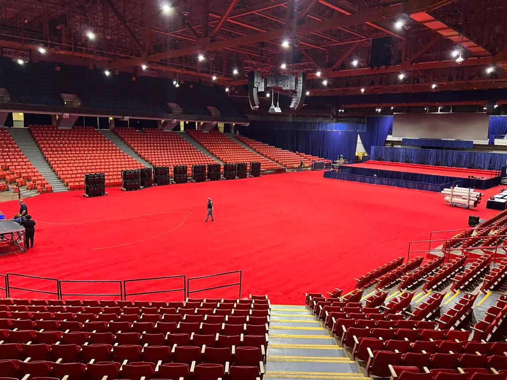 Large arena with red floor covering prepared for an event.