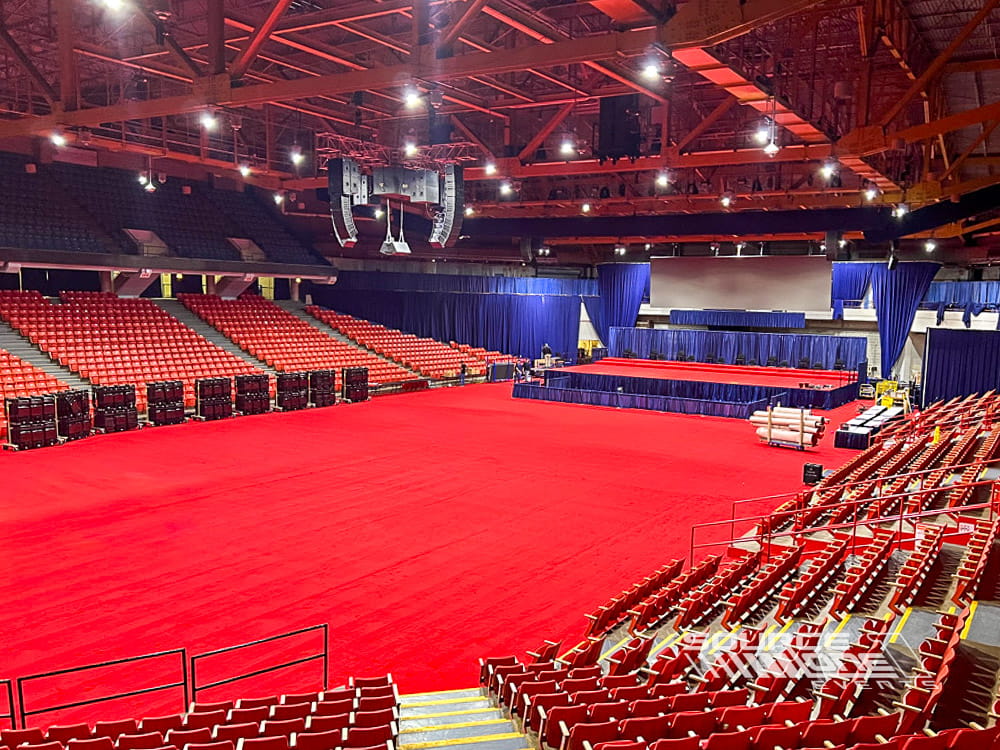 Wide view of commencement seating, stage, and custom event flooring inside an arena.