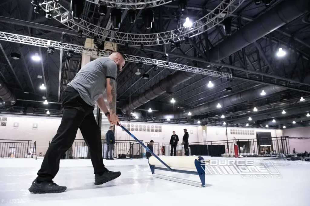 Crew member smoothing flooring during trade show setup.
