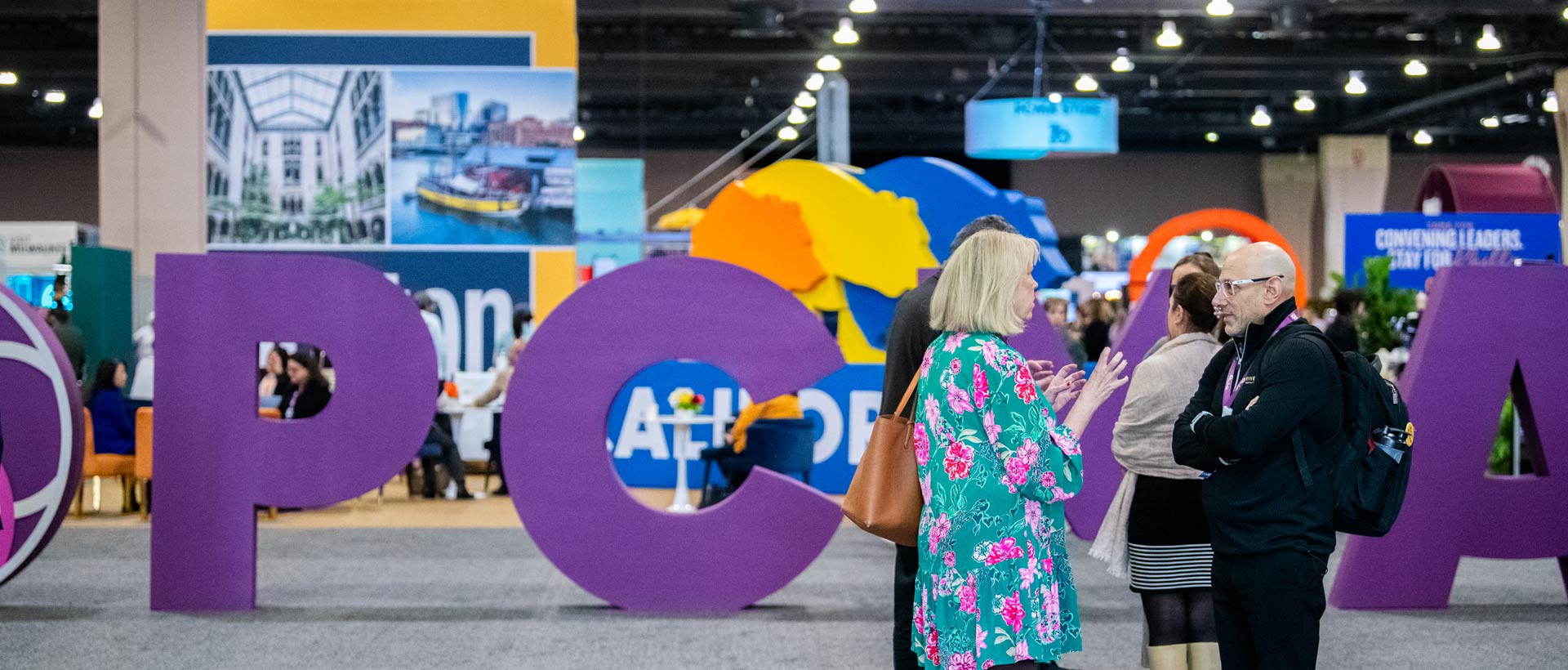 Attendees exploring colorful custom exhibit installations and interactive experiential activations on a convention show floor.
