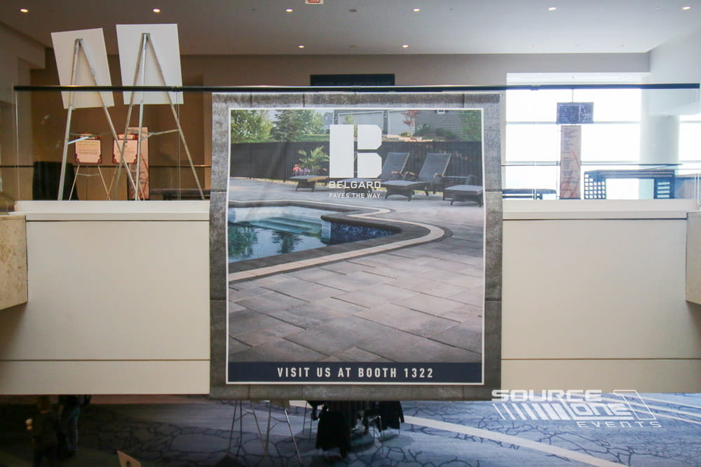 Large suspended fabric banner installed above the trade show floor featuring colorful event branding and wayfinding for iLandscape attendees.