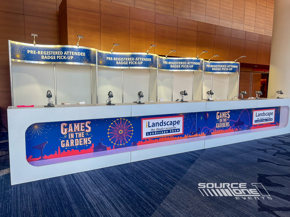 Large registration counter with blue branded graphics, multiple attendee check-in stations, and exhibit hall entrance signage.